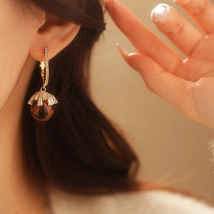 Detailed close-up of a golden hoop earring with a brown sphere and zircon crystals