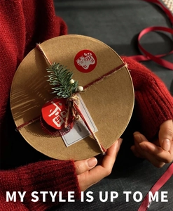 Close-up of round kraft paper gift box with pine branch, tiger sticker and red Fu tag