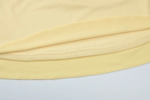 Detailed close-up showing double-layered stitching on the hem of a yellow V-neck dress