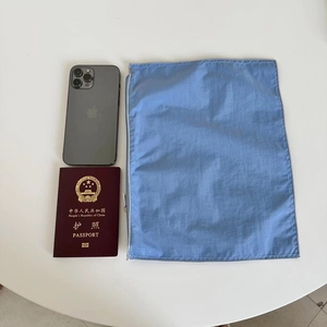 Blue nylon organizer pouch detail showing side zipper and size comparison on desk