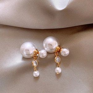 Elegant gold pearl drop earrings with sparkling zircon tassels on luxury champagne satin