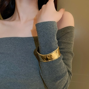Polished gold wide cuff bracelet with irregular wrinkled texture on a model's wrist
