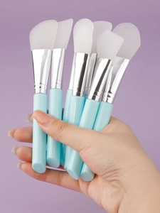 Detailed view of multiple silicone face mask brushes with light blue handles and silver ferrules