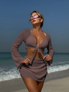 Dettaglio del set da spiaggia con top corto a maniche lunghe e gonna in rete a coulisse