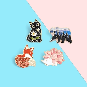Detailed view of enamel pins featuring a black cat, forest bear, red fox, and pink hedgehog