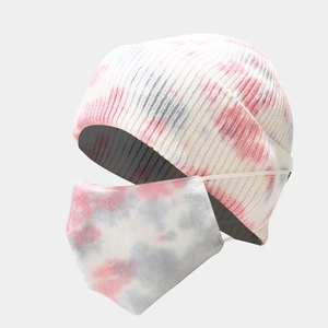 Close-up of tie-dye knit beanie and matching mask set with pink and grey patterns