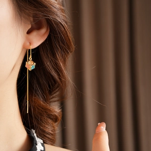 Close-up of gold plated ear threads featuring colorful cat eye stone cube pendants