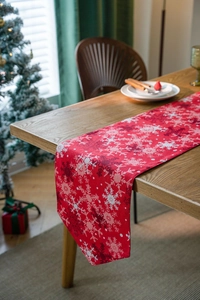 Close-up of red Christmas table runner with snowflake patterns on a rustic wooden table