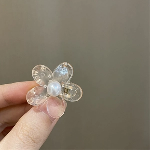 Primer plano detallado de una pequeña pinza para el cabello de flor transparente con perla blanca