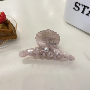 Shell-shaped acrylic hair claw clip in light pink with pearl detail and translucent finish