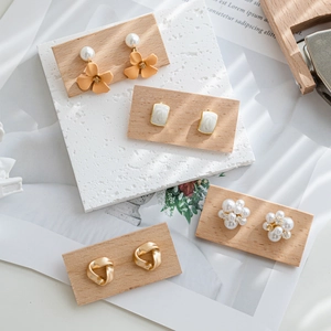 Artistic walnut display board showcasing assorted pearl and gold earrings in ins style