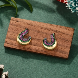 Détail de boucles d'oreilles dorées en U avec zircons colorés sur socle en bois