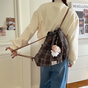 Detailed view of dark brown plaid backpack with cute lamb charm and drawstring closure