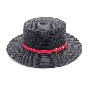 Detail of black boater straw hat with red faux leather band and gold buckle detail