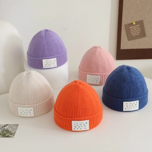 Close-up of candy-colored ribbed knit beanies with square letter patches in various colors