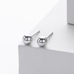 Detailed macro view of high-polish S925 sterling silver bead earrings on white blocks