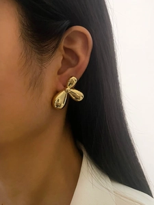 Close-up of elegant gold flower stud earrings in mirror finish on model's ear