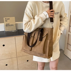Detail view of brown canvas tote bag featuring multi-pocket design and adjustable strap