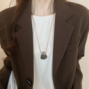 Detail of silver shell pendant with vertical stripes on a brown woven necklace cord
