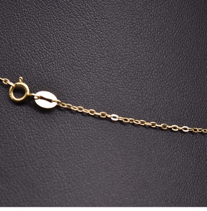 Macro shot of gold necklace spring clasp and oval metal tag on black leather texture