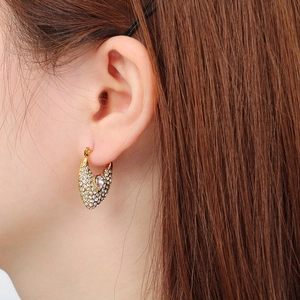 Gros plan de boucles d'oreilles évidées dorées avec strass et pierre en goutte