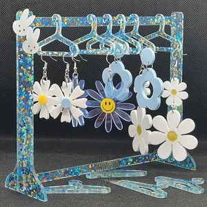 Detailed view of acrylic hanger jewelry stand with blue glitter and daisy earrings