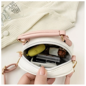 Internal view of a small white and pink round crossbody bag holding lipstick and cards