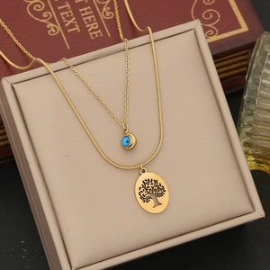Detail of gold double-layer necklace with blue evil eye and tree of life pendants