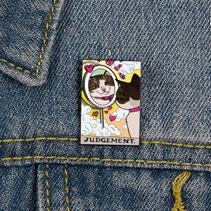 Close-up of Judgement Tarot Cat enamel pin on a denim jacket with cat mirror detail