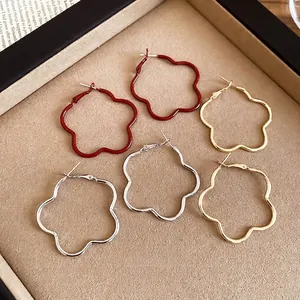 Retro red flower hoop earrings in gold and silver finishes on a beige display tray