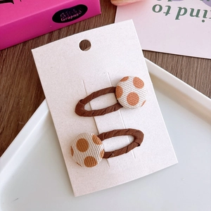 Detalle de pinzas para el cabello con botones florales marrón café y lunares naranjas