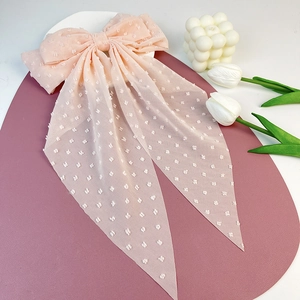 Elegant apricot swiss dot tulle bow hair clip with long flowing ribbons on purple display