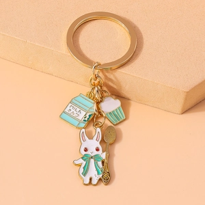Detailed view of a gold metal keychain with rabbit, milk carton, and cupcake charms