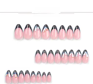 Macro detail of nude pink press-on nails with black glitter french tips and rhinestones