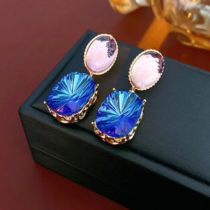 Vintage gold earrings with pink and blue gemstones in an ornate openwork floral design
