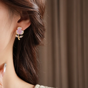 Detailed close-up of a purple flower stud earring with gold edging and zircon leaves