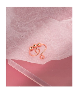 Macro shot of rose gold fidget ring with beads on pink textured surface