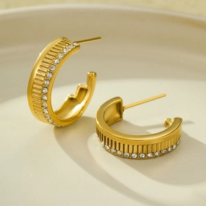 Close-up of 18K gold-plated C-shaped hoop earrings with striped texture and pavé zircon