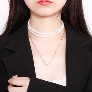Detail of layered gold chain with single pearl pendant and white pearl choker necklace