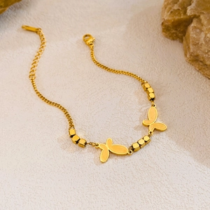 Détail d'un bracelet papillon doré avec des perles hexagonales sur un fond texturé