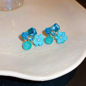 Détail macro de boucles d'oreilles fleurs bleues avec cristaux et perles sur plateau