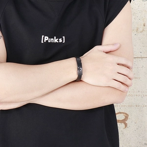 Detail of matte black punk bracelet featuring star cut-outs worn by a model