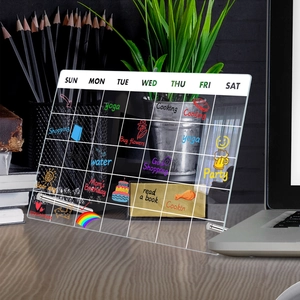 Detailed view of a clear acrylic weekly planner board on a wooden desk with metal supports