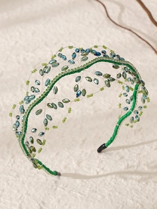 Dettaglio del cerchietto intrecciato a mano con perle in cristallo blu e maglia verde