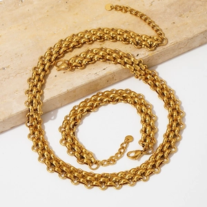 Gold stainless steel punk chunky chain necklace and bracelet set on stone platform