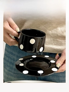 Détail d'un ensemble tasse à café et soucoupe en céramique à pois noirs et blancs