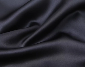 Gros plan sur le tissu en satin de soie noire montrant une texture lisse et drapée