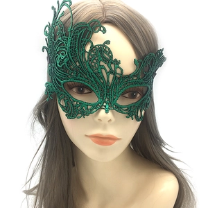 Close-up of green lace masquerade mask with intricate floral pattern and bronzing details