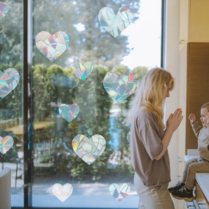 Rainbow prism window film in heart shapes showing colorful reflections on glass pane