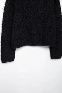 Détails de la veste en laine noire avec bordures en cuir sur l'ourlet et les poignets